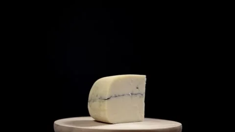 A wedge of Morbier cheese rotating with a black background Stock Footage 241504758