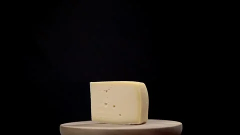 A wedge of raclette cheese rotating with a black background Stock Footage 241498232