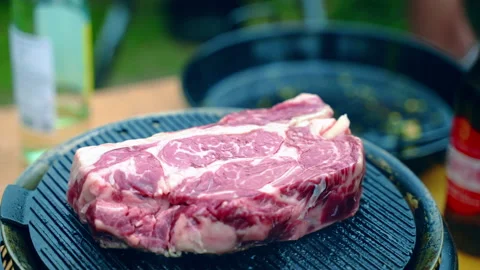Weekend bbq party under the open air, raw bloody prime beef steak roasting and Stock-Footage 157050501