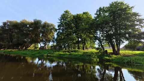 Weekend kayaking. Scenic view of a calm river reflecting lush green trees and a Stock Footage 346782127