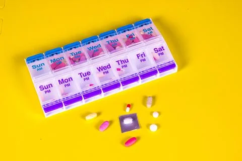 Weekly Pill Box Container On Smooth Yellow Background Stock Photos