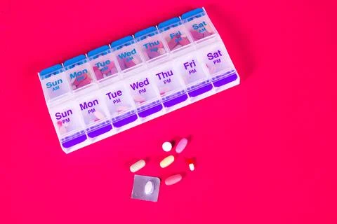 Weekly Pill Box Container On Smooth Red Background Foto stock