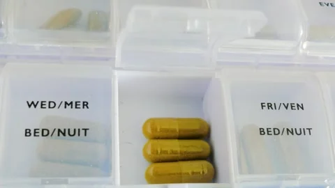 Weekly pill organizer box with brown capsules in open compartment Видео 335849553