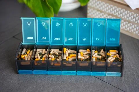 Weekly pill organizer with labeled compartments for daily medication doses Stock Photos