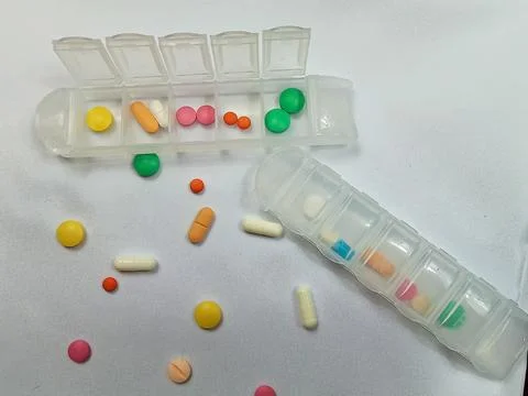 Weekly Pill Organizers with Assorted Tablets on White Background Stock Photos