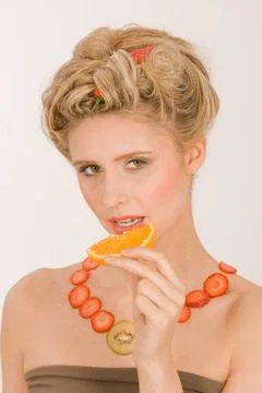 Weibliche Früchte Junge Frau mit Halskette aus Erdbeeren und Kiwi isst ein.. Stock Photos