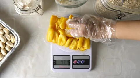 Weighing and packaging fresh pitted jackfruit meat on kitchen table Stock Footage 154383160