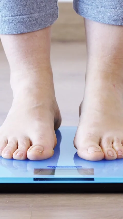 Weighing herself on a scale Stockbeeldmateriaal 335240937