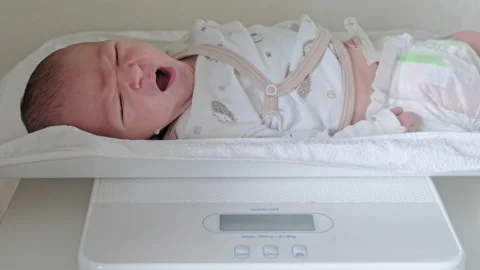 Newborn baby on weight scale in hospital Stock Photo