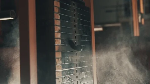 Weight falling in block machine and cloud of powder raising in dark gym in slomo Stock Footage 92135108
