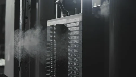 Weight falling in block machine and cloud of powder raising in dark gym in slomo Stock Footage