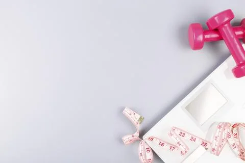 Weight loss concept flat lay with scales, dumbbells and measuring tape on grey Stock Photos
