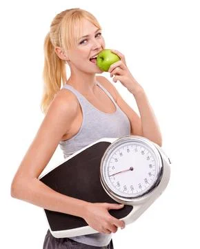 Weight-loss through healthy eating. A woman holding a scale and eating an apple. Stock Photos