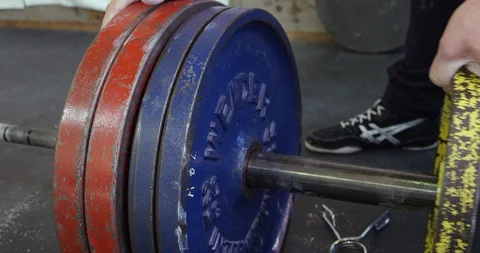 Weightlifter adding plates to deadlift bar. Stock Footage 113684027