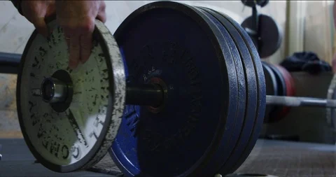 Weightlifter adding plates to deadlift bar Stock Footage 113684044