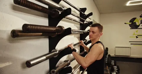 A weightlifter with a barbell puts it back after training. Video stock 277621823