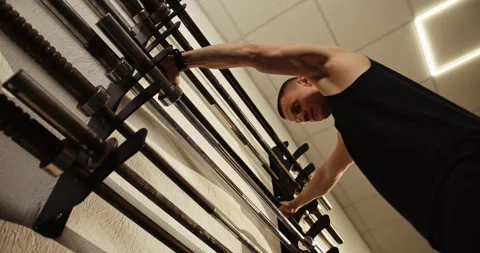 A weightlifter with a barbell puts it back after training. Stock Footage 277621833