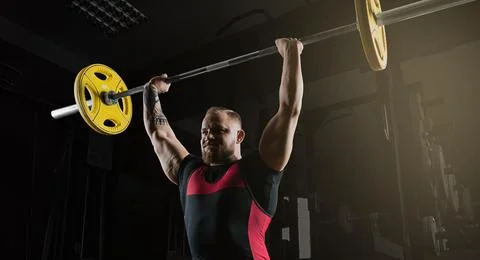 Weightlifter does an exercise with a barbell. Stock Photos