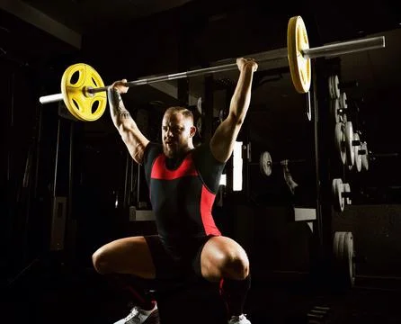 Weightlifter does an exercise with a barbell. Stock Photos