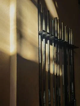 Weightlifting bars attached to the wall with a ray of sunlight coming through Stock Photos