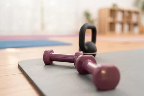 Weights and kettlebell resting on exercise mat in studio during workout sessi Stock Photos