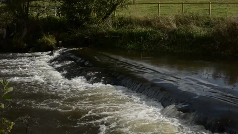 A Weir On A River Flowing Through Farmland Stock Footage 163369006
