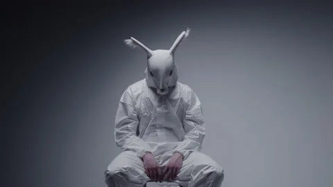 Weird stranger in a white rabbit mask sitting on a chair. Mad man. Stock Footage 148486859