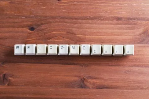 Welcome 2018 new year on computer keyboard keys buttons on wooden background Foto stock