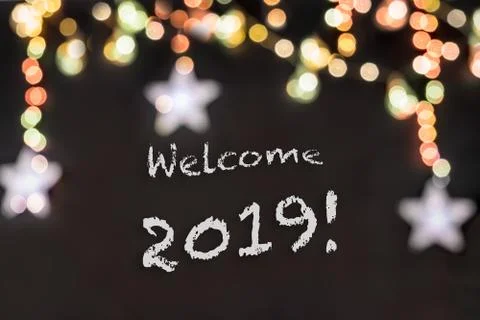 Welcome 2019 text in a black background with lights and stars. Stock Illustration