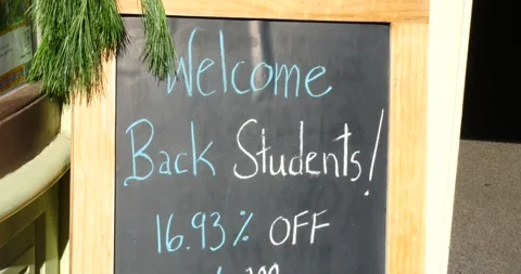 Welcome back students sign promoting discounts outside local store Stock Footage 281704890