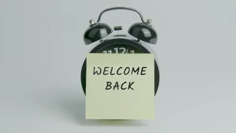 Welcome Back Text or Word on Yellow Note Paper Sticking onto Black Clock Stock Footage 299869084