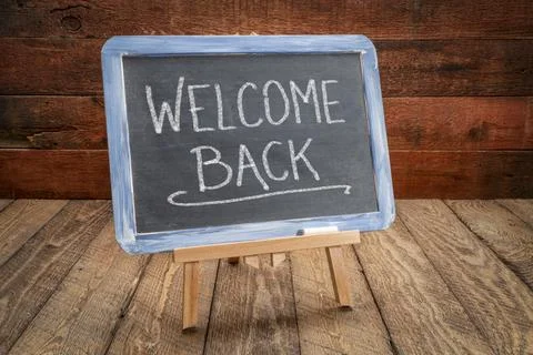 Welcome back - white chalk handwriting on a slate blackboard Stock Photos