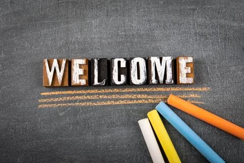 Welcome. Different colored chalks on a black chalk board Stock Photos
