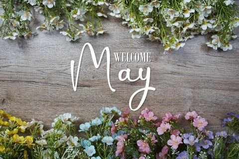 Welcome May text with flowers frame on wooden background Stock Photos