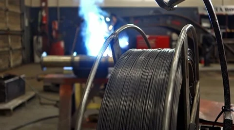 Welder in backdrop of spinning flux core wire feeder. Stock Footage 45425406
