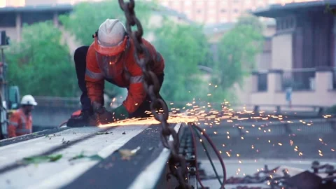 Welder / Construction Worker welding steel on a beam on a busy urban street Stock Footage 131136689