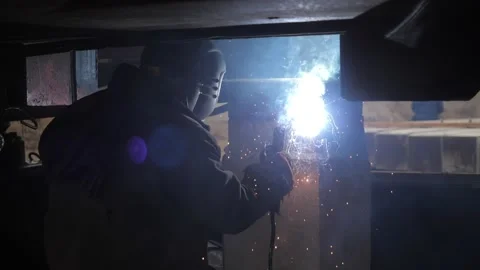The welder is doing the welding. The welding machine creates sparks. Stock Footage 164922138
