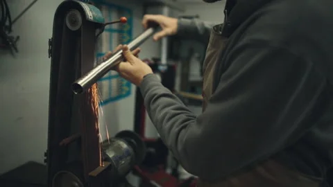 Welder grinds metal tube creating sparks Stock Footage