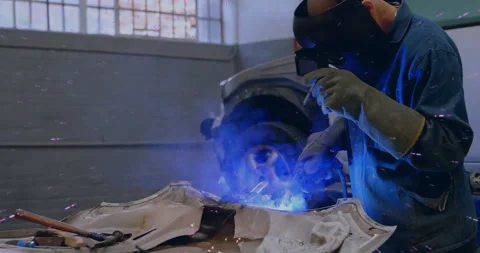Welder igniting torch and guiding arc along panel seam in auto shop inspecting Video stock 312694947