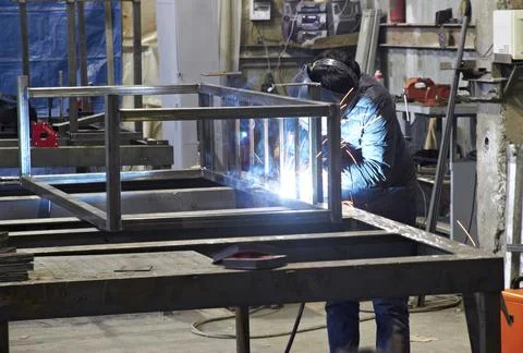 Welder makes a metal structure in a workshop Stock Photos