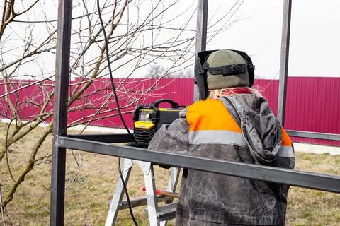 The welder makes welding of metal structures from a profile pipe with an el.. Stock Photos