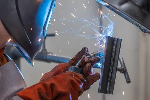 Welder man welding a metal, using a blowtorch, electric arc, or other means, and Stock Photos