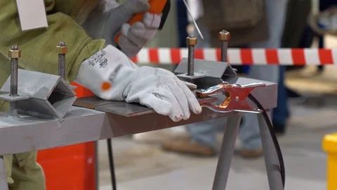 Welder man welds two small metal plates lying on a makeshift workbench closeup Stock Footage 126356872