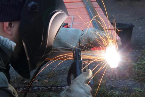 Welder in the mask while working. Welder craftsman makes a metal frame in the Stock-Fotos