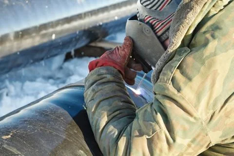 Welder performs welding pipeline in winter conditions Fotos de archivo