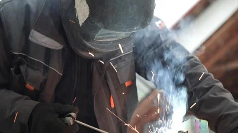Welder in protective helmet uses welding. Welder Welds a metal pipe Stock Footage 263218906