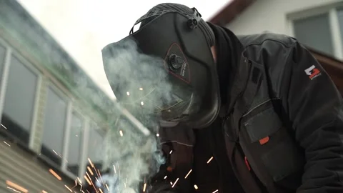 Welder in protective helmet uses welding. Welder Welds a metal pipe Stock Footage 263218921