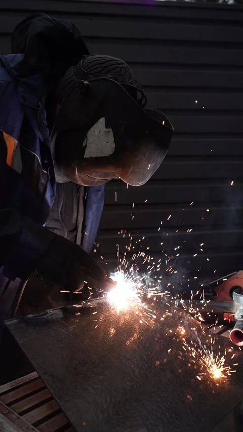 Welder in protective helmet uses welding. Welder Welds a metal pipe Stock Footage 263219081