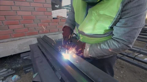 Welder in protective mask gloves and vest works with metal steel and iron. Stock Footage 230979945