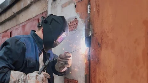 Welder in protective mask welding metal door Stock-Footage 333697232